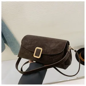 Close-up of a dark brown suede shoulder bag with a stylish golden square metal buckle
