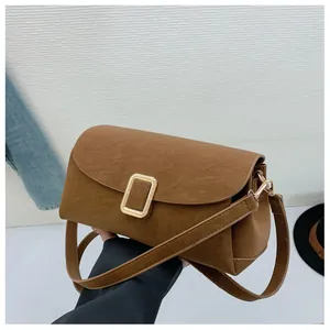 Detail of brown suede shoulder bag with elegant gold metal buckle and vintage texture