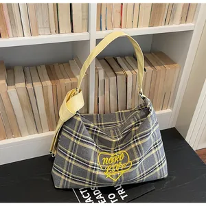 Detail of yellow heart embroidery on grey and yellow checkered tote bag with canvas strap