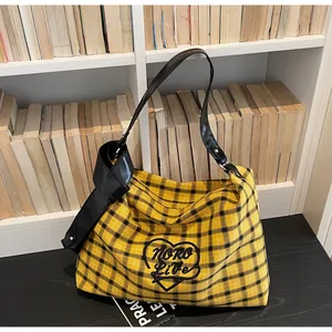 Detail of yellow plaid tote bag featuring heart embroidery and knotted leather strap