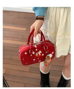 Detail of red Boston bag featuring star embroidery and a cute brown teddy bear charm