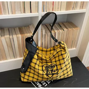 Detail of yellow plaid tote bag featuring black heart embroidery and knot PU leather strap