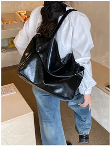 Makroaufnahme einer glänzend schwarzen Hobo-Tasche mit öliger Oberfläche und Falten