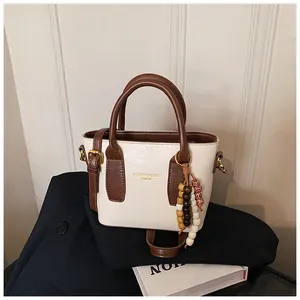 Detailansicht der Vintage-Beuteltasche aus beigem Kunstleder mit Holzperlenanhänger