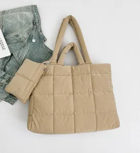 Detail van gewatteerde puffer tote tas in beige met bijpassend tasje en spijkerjasje