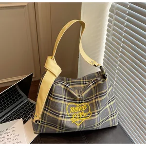 Detail of plaid tote bag featuring yellow heart patch and knotted leather strap