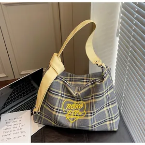 Detail of plaid tote bag featuring yellow heart embroidery and stylish knotted shoulder strap