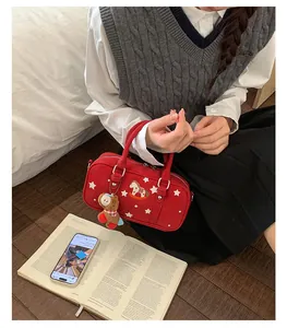 Detail of red Boston bag featuring star embroidery and a cute brown plush bear pendant