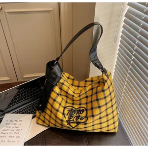 Detail of yellow plaid tote bag featuring heart embroidery and large black PU knot shoulder strap