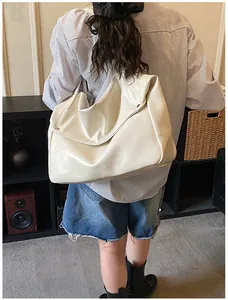 Detailansicht der großen cremefarbenen Ledertasche mit breitem Schultergurt und weicher Textur