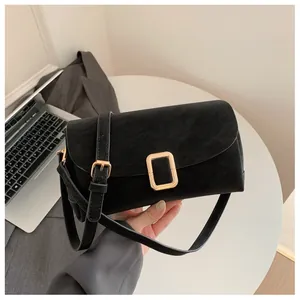 Detail of black rectangular suede shoulder bag with a premium golden metal buckle