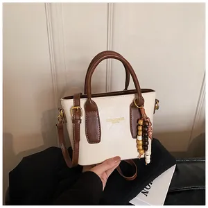 Detail der Vintage-Tragetasche mit Kontrastnähten und elegantem Perlenanhänger