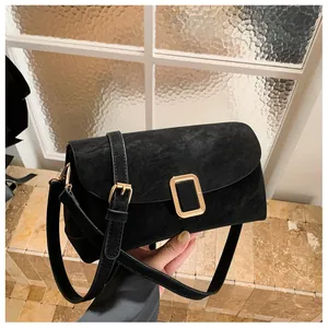 Detail view of black textured leather square bag with elegant gold buckle and strap