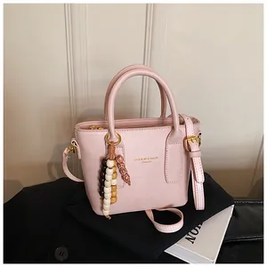 Detail der rosa PU-Leder Beuteltasche mit Goldschrift und buntem Perlen-Quastenanhänger