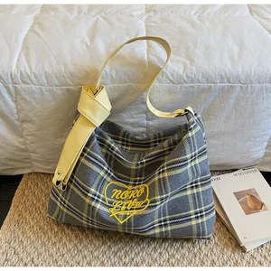 Close-up of checkered tote bag with yellow leather strap and heart embroidery detail