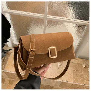 Detail of vintage brown suede crossbody bag featuring elegant gold square buckle hardware