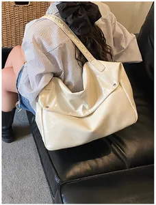 Detail einer großen elfenbeinfarbenen Lackleder-Tasche mit breitem Schultergurt