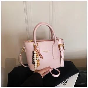Detail der hellrosa PU-Leder Handtasche mit Perlenquaste und goldenem Mode-Logo