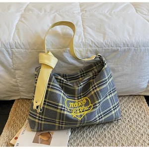 Detail of checkered tote bag featuring leather knotted strap and Noro Live embroidery
