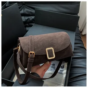 Detail of vintage dark brown suede crossbody bag featuring a classic gold rectangular buckle