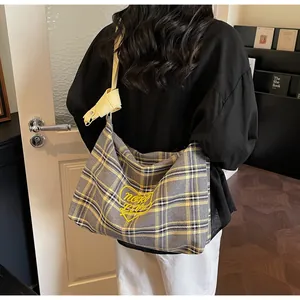 Detail of checkered hobo bag featuring yellow heart embroidery and wide shoulder strap