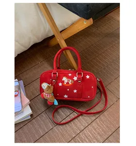 Detail of red Boston bag with star print, rocking horse embroidery and plush charm