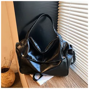 Detail der glänzenden schwarzen Hobo-Tasche aus Leder mit weichen Falten und Tragegurt