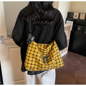 Detail of yellow plaid tote bag with heart embroidery and black leather shoulder strap