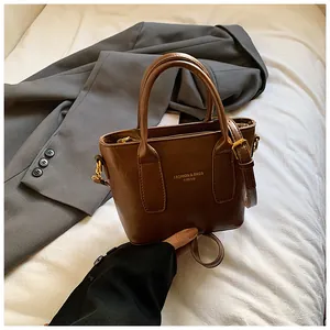 Detail der dunkelbraunen Vintage-Lederhandtasche mit Goldaufdruck und Metallbeschlägen