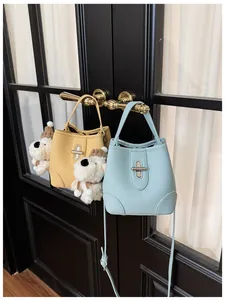 Close-up of litchi pattern leather bucket bags with metal twist locks and plush puppy charms
