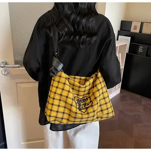 Close-up of yellow checkered tote bag with heart patch and knot strap detail