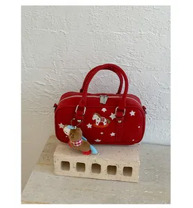 Detail of red Boston bag with star prints, rocking horse patch and plush charm