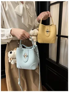 Detail of lychee textured bucket bag with silver twist lock and plush puppy charm