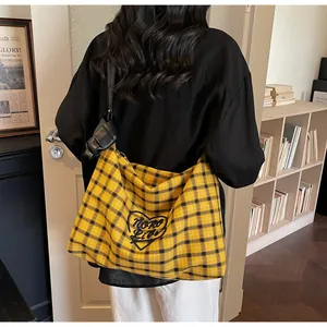 Detail of yellow checkered tote bag with heart embroidery and black leather strap