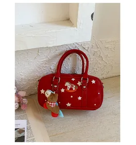 Detail of red Boston bag featuring white star prints and a plush horse keychain charm