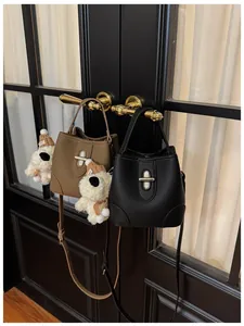 Detail of stylish bucket bags in black and brown leather with metallic twist locks