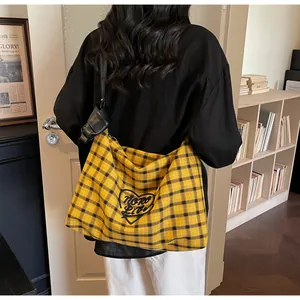 Detail of yellow checkered tote bag with heart embroidery and black shoulder strap
