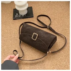 Detail of dark brown matte leather crossbody bag with a gold square metal buckle