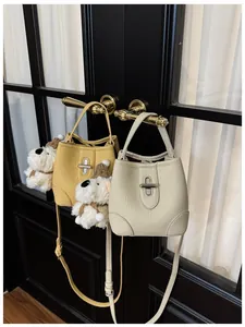 Detail of leather bucket bags with metal turn-lock and cute plush dog charms