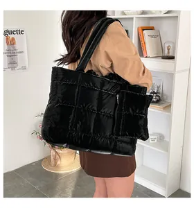 Détail d'un grand sac cabas matelassé noir avec pochette assortie dans un décor moderne
