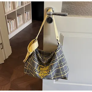 Detail of yellow and grey plaid hobo bag featuring heart embroidery and bow on door handle