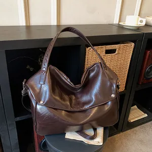 Große braune Ledertasche mit geflochtenen Griffen und Nieten für den täglichen Weg