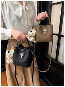 Detail of bucket bags featuring textured pebble leather and a cute plush dog pendant