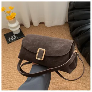 Detail of dark brown matte leather shoulder bag with gold square buckle and strap