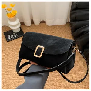 Detail of matte black suede crossbody bag featuring a classic gold rectangular metal buckle