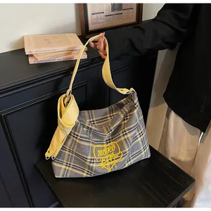 Detail of yellow plaid tote bag featuring heart embroidery and a knotted shoulder strap