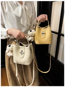Close-up of pebble leather bucket bags in cream and yellow with metal turn-lock closures