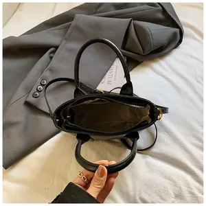 Draufsicht der schwarzen Handtasche mit Reißverschlussfach und braunem Innenfutter-Detail