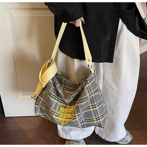 Detail of checkered tote bag with yellow heart embroidery and leather knot shoulder strap
