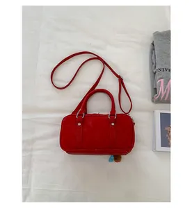 Close-up of red Boston bag with matte leather finish, silver hardware, and plush charm